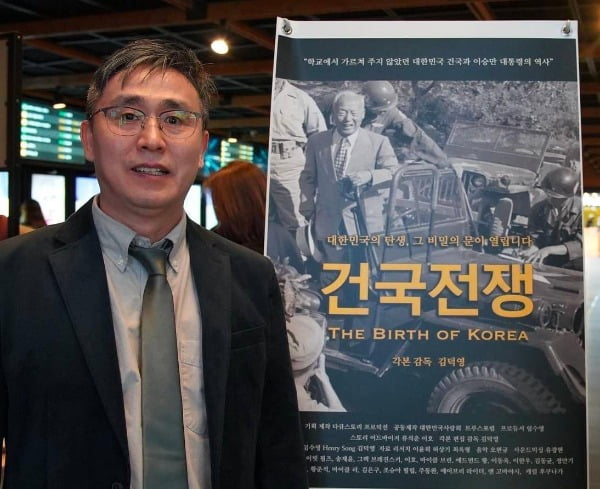 영화 '건국전쟁'을 연출한 김덕영 감독이 영화 홍보 포스터 앞에서 포즈를 취하고 있다. /다큐스토리 제공 
