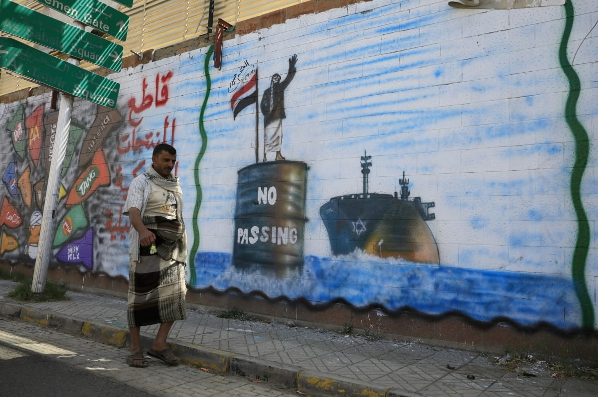 19일(현지) 예멘 후티반군 거점인 사나에서 한 사람이  이스라엘 선박을 저지하는 후티 반군을 묘사한 낙서 앞을 지나고 있다. /EPA
