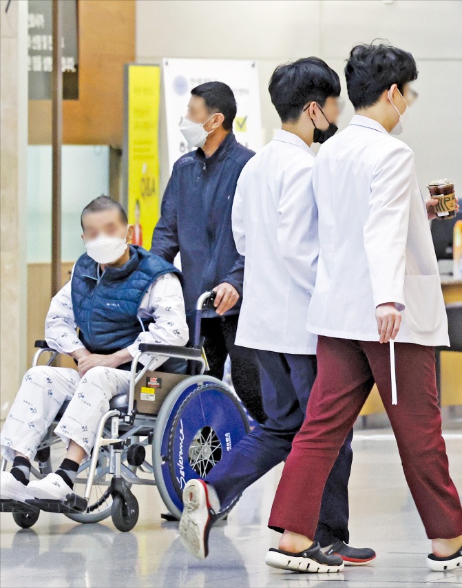 18일 서울의 한 대학병원에서 휠체어를 타고 이동하는 환자 옆을 의료진이 지나가고 있다. 주요 서울 대형 대학병원 전공의들이 집단 사직하면서 의료대란 우려가 커지고 있다.  이솔 기자 