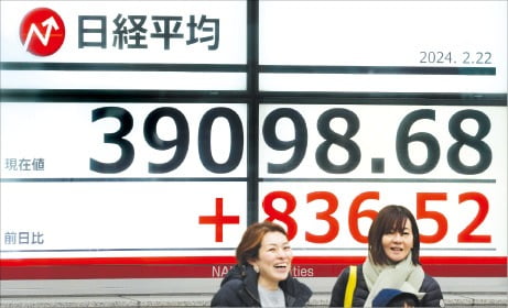 일본 닛케이지수가 신기록을 경신한 지난달 22일 도쿄 시내의 증시 전광판 앞을 시민들이 지나가고 있다.  EPA연합뉴스 