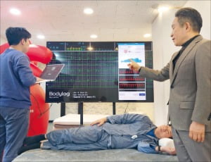 김인호 럭스나인 대표(오른쪽)가 서울 방배동 연구개발센터에서 헬스케어 웨어러블 기기 ‘바디로그’를 착용한 사용자의 심전도 수치를 설명하고 있다.  럭스나인 제공 