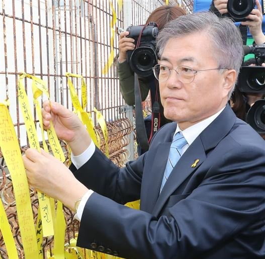 2017년 당시 문재인 더불어민주당 대선후보가 전남 목포 신항만 담장에 노란 리본을 매달고 있다. / 사진=연합뉴스