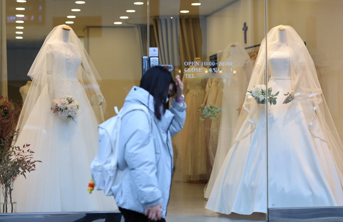 서울 아현동 웨딩거리에 있는 웨딩드레스 판매점 앞을 한 시민이 지나가고 있다.  사진=연합뉴스