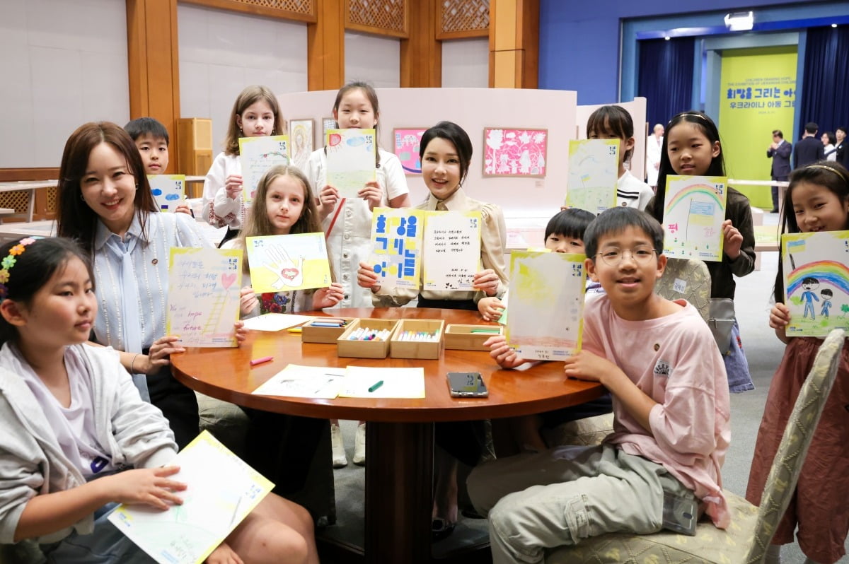 윤석열 대통령 부인 김건희 여사가 21일 청와대 춘추관에서 열린 '희망을 그리는 아이들: 우크라이나 아동 그림전'을 찾아 아이들과 함께 희망의 메시지를 들고 기념촬영을 하고 있다. 대통령실 제공