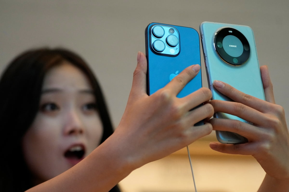 2023년 9월 중국 상하이의 애플 스토어에서 한 고객이 아이폰15프로와 화웨이 메이트60프로를 살펴보고 있다. /REUTERS