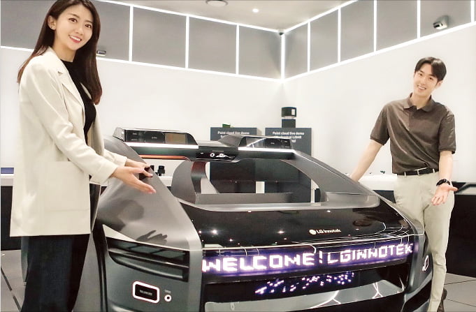 LG이노텍 직원들이 13일 미래차 목업(제품 일부를 모형으로 만든 것)에 장착한 차량용 입체 조명 모듈 ‘넥슬라이드’에 대해 설명하고 있다.  LG이노텍 제공 