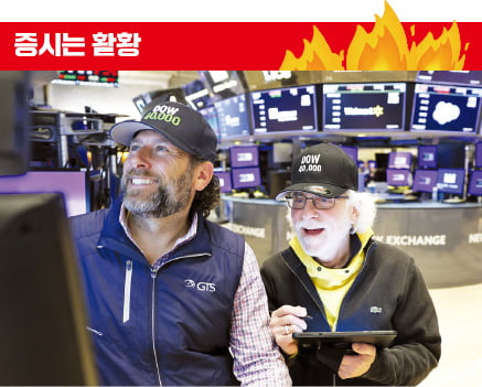 지난 16일 뉴욕증권거래소(NYSE)에서 트레이더들이 ‘다우(DOW) 40,000’이라고 적힌 야구 모자를 쓰고 일하고 있다. 다우존스지수는 이날 사상 처음으로 장중 4만 선을 돌파했다.  AFP연합뉴스 