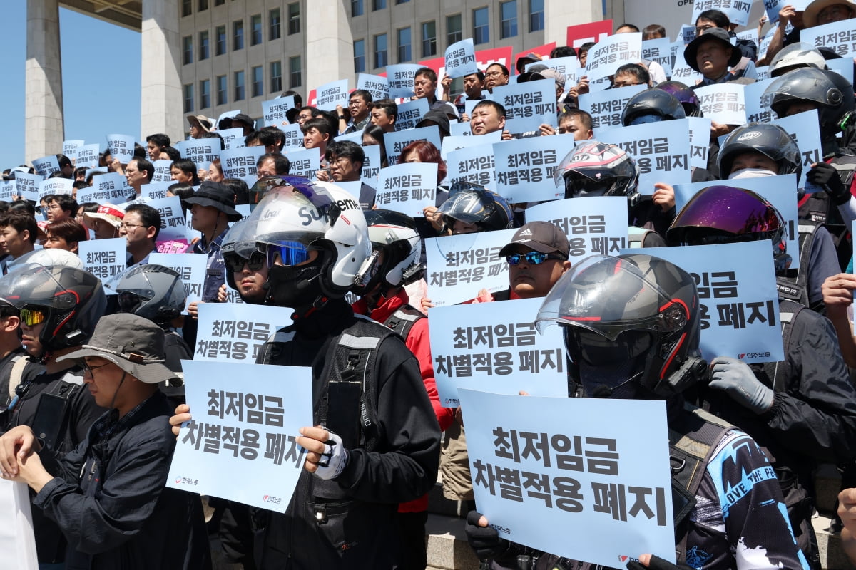 배달기사들이 3일 국회 본청 앞에서 '최저임금 차별금지법 국회 선포' 기자회견에 참석하며 '최저임금 차별적용 폐지'가 적힌 손팻말을 들고 있다/ 사진=강은구 기자