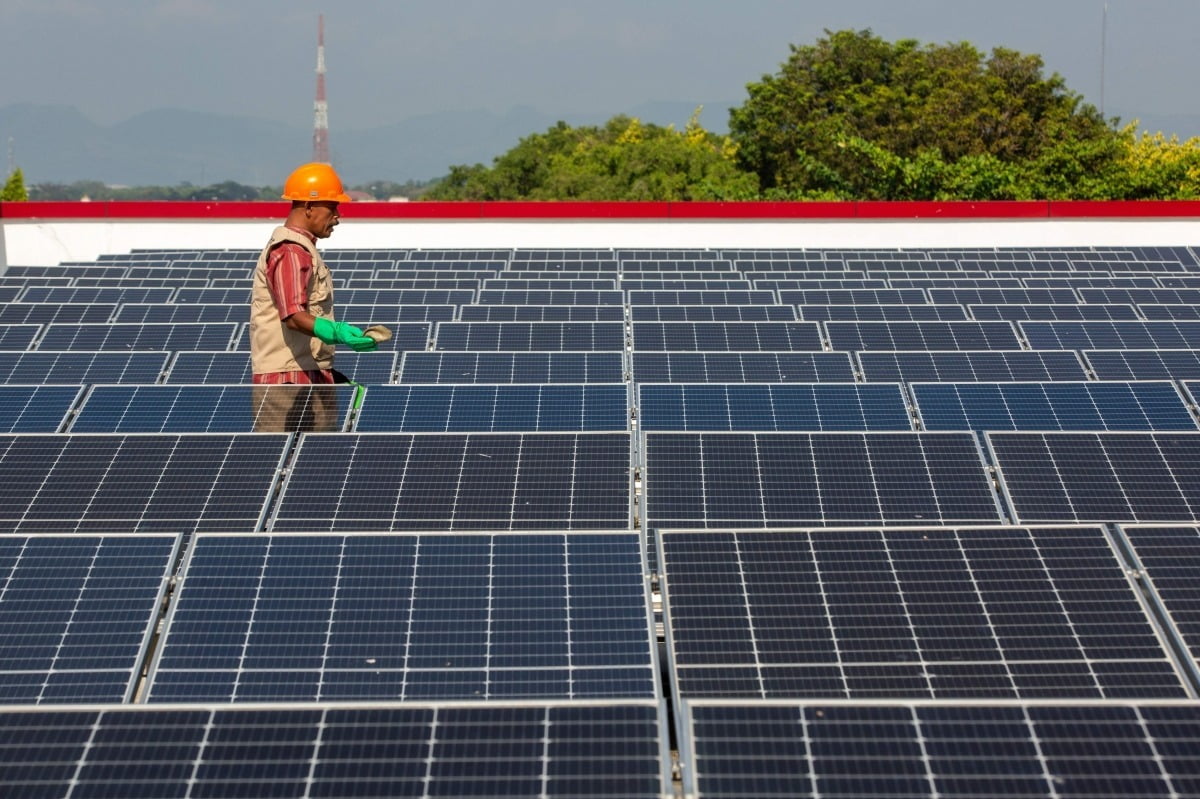 지난달 20일 인도네시아 중부 자바 클라텐의 게데 전통시장 지붕에 설치된 태양광 패널을 한 인부가 청소하고 있다. /AFP