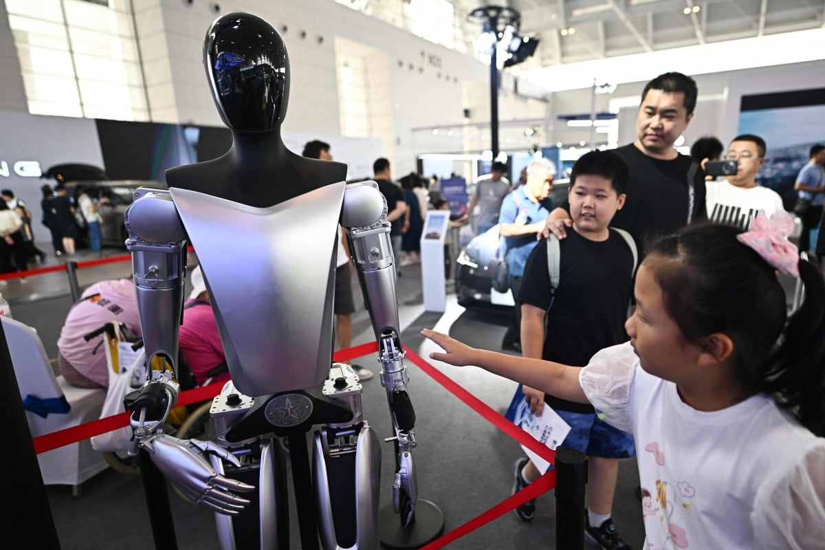 지난 6월 중국 톈진에서 열린 세계 정보 엑스포에서 관람객들이 테슬라의 인간형 로봇 '옵티머스'를 살펴보고 있다. /AFP