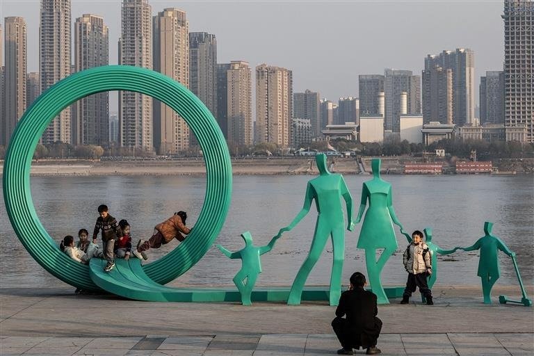 지난 1월 중국 후베이성 우한 한커우 공원에서 '한 부모 세 자녀 동상'에서 아이들이 놀고 있다. /AFP