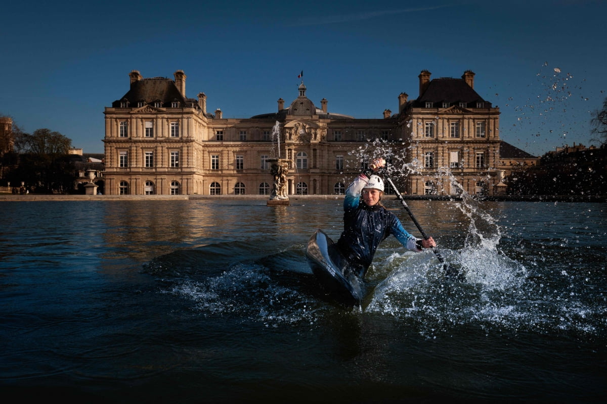 France's canoeist Marjorie Delassus poses inside the fountain of the Jardin du Luxembourg (Luxembourg Garden) with the French Senate in the background in Paris on March 25, 2024, ahead of the Paris 2024 Olympic and Paralympic games. Since 1799, the Palais du Luxembourg (Luxembourg palace) has been home to the Senate, the upper chamber of the French Parliament . From 1879, the Jardin du Luxembourg (Luxembourg Garden) has been assigned to the Senate, which is responsible for its management, supervision and conservation. AFP