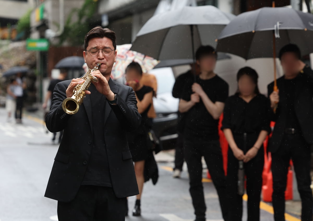 대학로 소극장의 상징 '학전'을 30여년간 운영하며 후배 예술인을 배출해 온 가수 김민기의 발인식이 엄수된 24일 오전 서울 종로구 아르코꿈밭극장 앞에서 색소포니스트 이인권씨가 김민기의 곡 '아름다운 사람'을 연주하고 있다. /연합뉴스