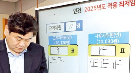 2026년 최저임금이 시간당 1만30원으로 결정된 직후 이인재 최저임금위원장이 투표 결과가 적힌 게시판 앞을 지나가고 있다.  연합뉴스 