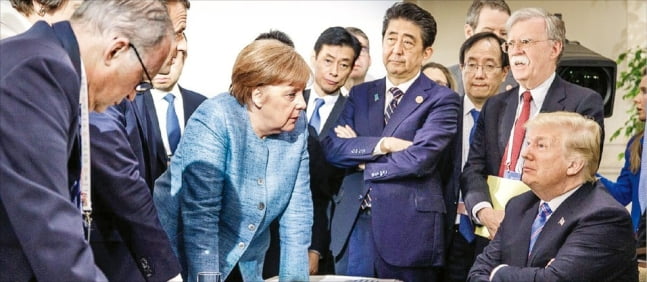 앙겔라 메르켈(왼쪽 세번째) 전 독일 총리가 2018년 6월 캐나다 퀘벡주에서 열린 주요 7개국(G7) 정상회의 회의장에 앉아있는 도널드 트럼프 전 미국 대통령(오른쪽 첫번째)과 대화하고 있다./연합뉴스