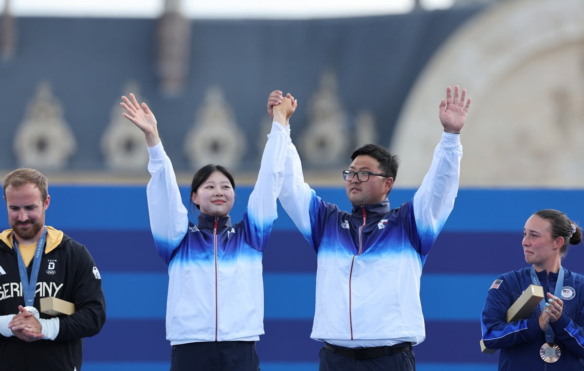  2일(현지시간) 프랑스 파리 레쟁발리드에서 열린 2024 파리올림픽 양궁 혼성 단체 시상식에서 김우진과 임시현이 금메달 수상 전 시상대에 올라 관중을 향해 인사하고 있다.  /연합뉴스