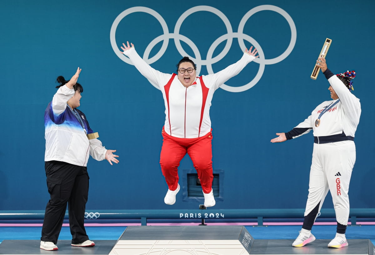 Park Hae-jung, membro da Equipe Nacional de Halterofilismo da Coreia, e Emily Campbell, da Grã-Bretanha, comemoram enquanto a chinesa Li Wenwen, medalhista de ouro, sobe ao pódio na cerimônia de levantamento de peso feminino de 81 kg nas Olimpíadas de Paris 2024, realizada na South Paris Arena 6, em Paris , França. 11 (horário coreano)./image = notícia 1