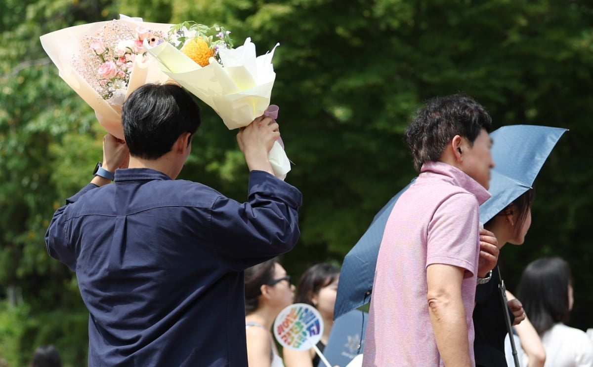 23일 서울 용산구 숙명여자대학교에서 열린 2023학년도 후기 학위수여식에서 한 졸업생의 가족이 꽃다발로 햇볕을 가리고 있다. /이솔 기자