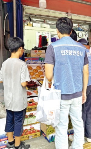 인천항만공사 직원이 저소득 가정의 아동과 함께 전통시장에서 장보기를 하고 있다.  인천항만공사 제공 