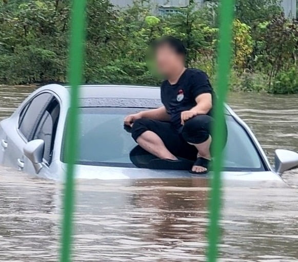 지난 21일 호우특보가 발효된 경남 김해에서 도로가 침수돼 한 남성이 차량 위로 대피해있다. 아래엔 흙탕물이 높게 차올라 차량 보닛이 거의 다 잠긴 상태다. 사진=카지노 가입머니1