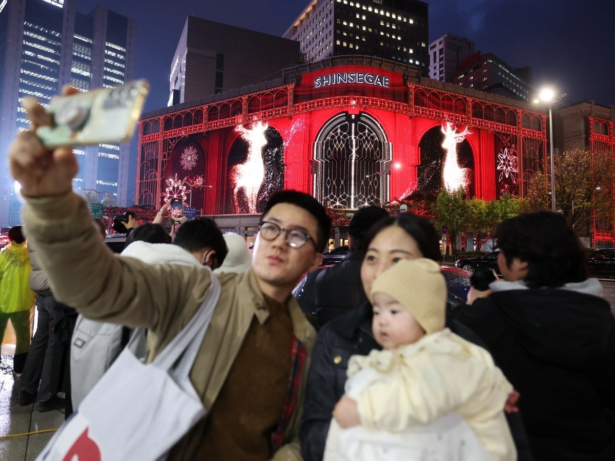 지난해 11월 시민들이 서울 회현동 신세계백화점 본점 외벽의 크리스마스 시즌 미디어 파사드를 배경으로 기념촬영하는 모습. / 사진=한경 DB