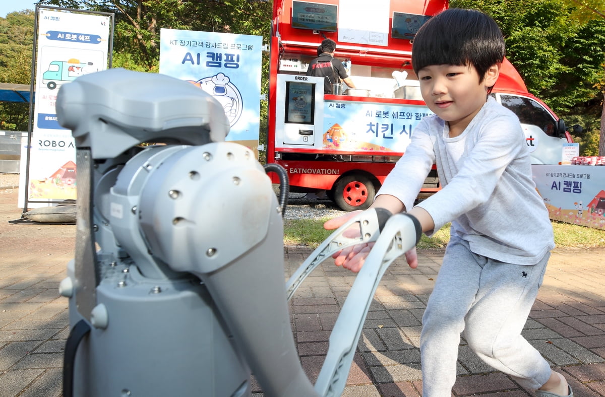 KT가 지난 11일 강원 횡성군 KT 전용캠핑장에서 진행한 행사인 'AI와 함께하는 초대그림 캠핑' 에서 한 아이가 KT의 로봇 기술을 체험하고 있다. KT 제공