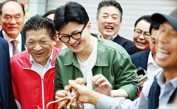 < 낙선인사 간 韓 > 한동훈 국민의힘 대표가 18일 전남 곡성 기차마을전통시장에서 한 상인이 낙지를 건네자 웃고 있다. 이날 한 대표는 10·16 재·보궐선거에서 패배한 최봉의 후보와 함께 주민들을 만나 낙선 인사를 하며 “한 번만 더 기회를 주시면 좋겠다”고 말했다. /연합뉴스 