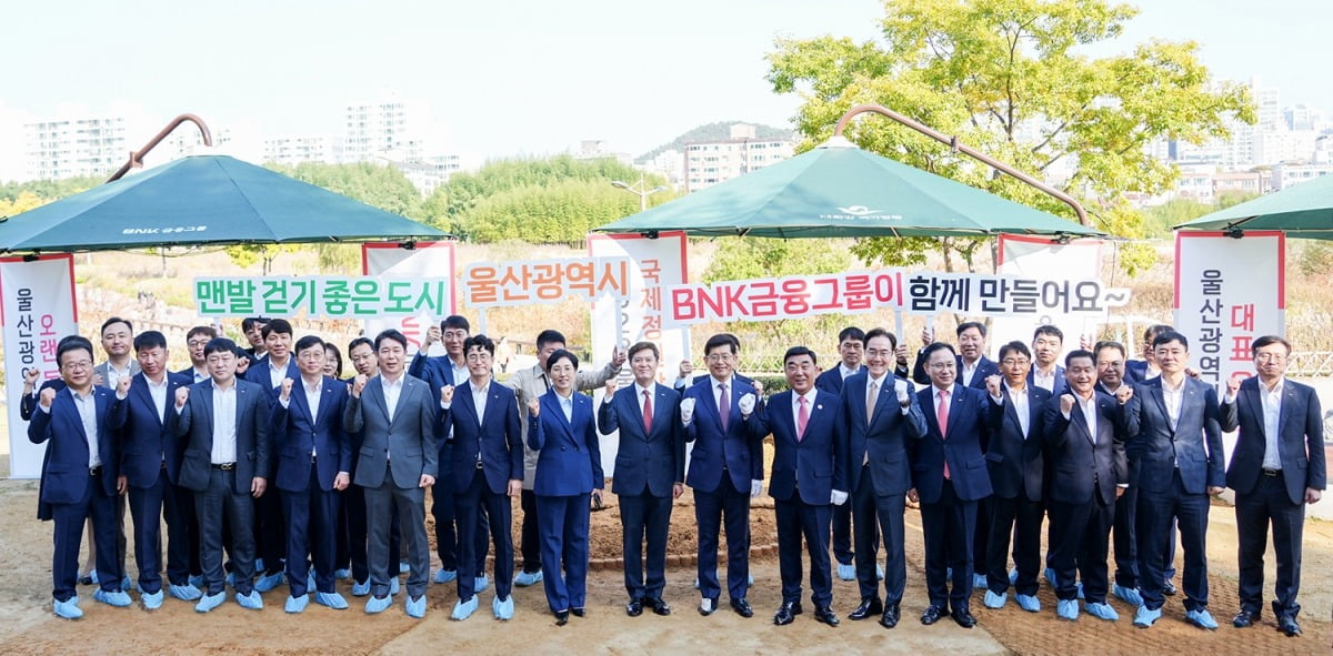 BNK금융그룹이 12일 울산 태화강에서 ‘태화강 국가정원 맨발걷기길 및 그늘막 재개장식’을 개최했다. 왼쪽 아홉번째부터 BNK금융그룹 빈대인 회장, 김두겸 울산시장,  경남은행 예경탁 은행장. BNK 경남은행 제공