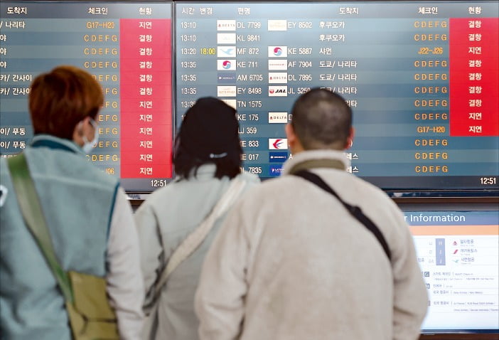 < 비행기 결항·지연 > 28일 인천국제공항 제2여객터미널에서 여행객들이 결항 및 지연 안내가 줄줄이 뜬 전광판을 바라보고 있다.  연합뉴스 