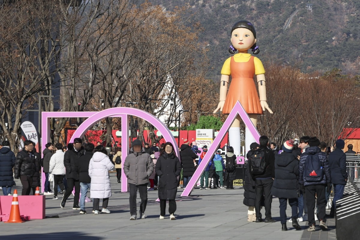 오징어게임2가 전세계 공개를 앞둔 26일 서울 종로구 광화문광장에 설치된 넷플릭스 오리지널시리즈 '오징어게임2'의 대표 캐릭터 '영희' 조형물 앞을 시민들과 외국인 관광객들이 지나고 있다.