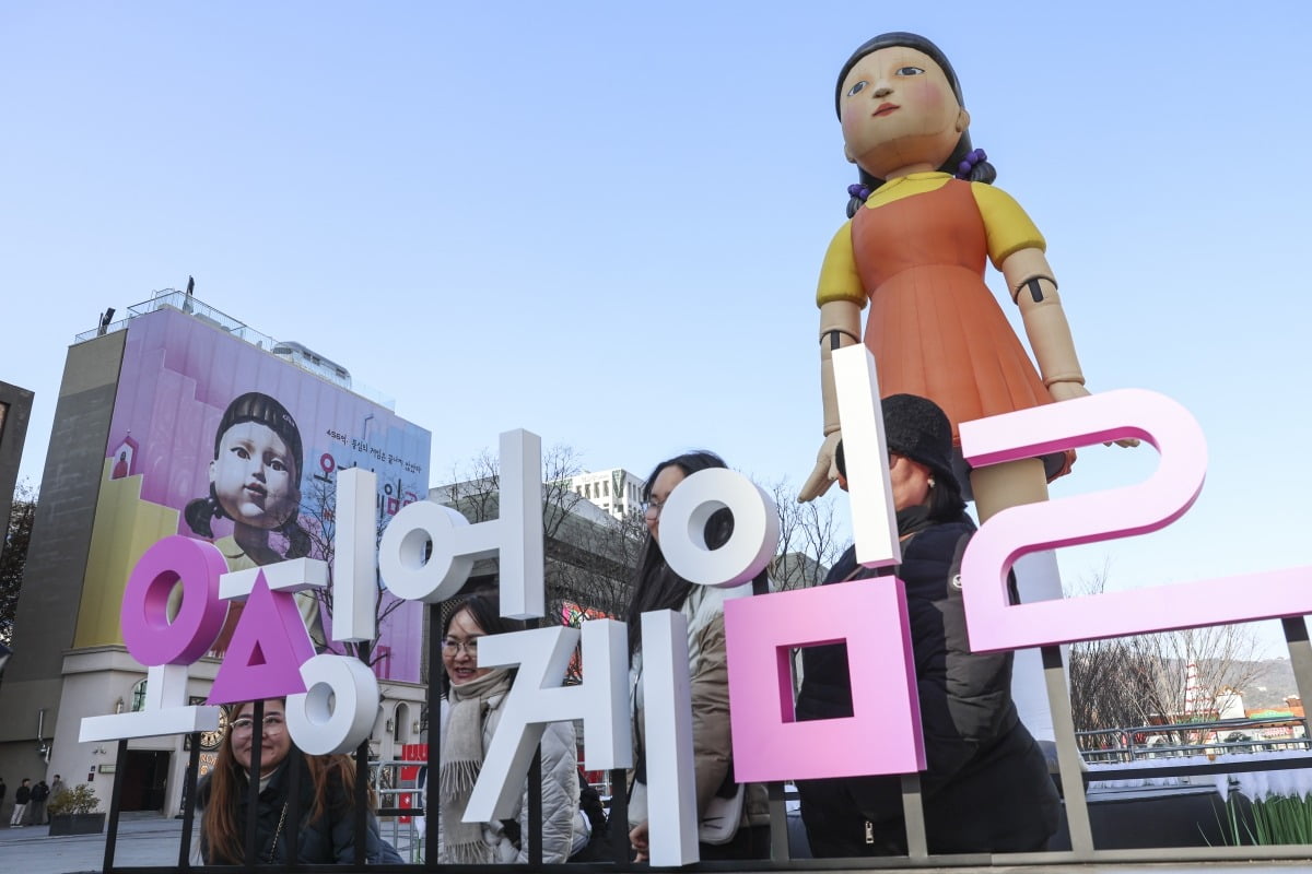 오징어게임2가 전세계 공개를 앞둔 26일 서울 종로구 광화문광장에 설치된 넷플릭스 오리지널시리즈 '오징어게임2'의 대표 캐릭터 '영희' 조형물 앞에서 외국인 관광객들이 기념사진을 찍고 있다.