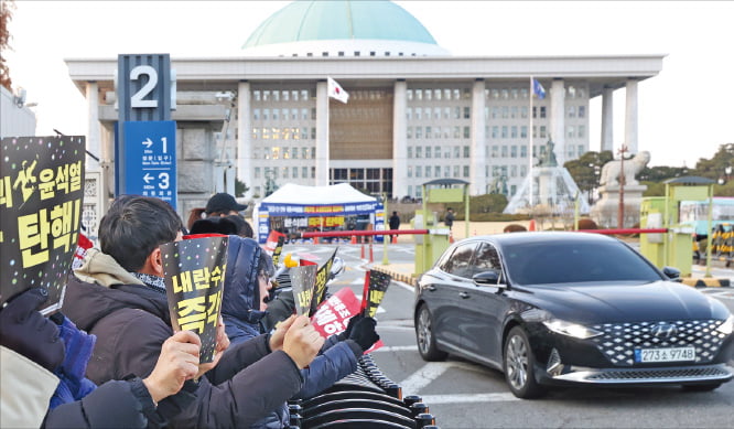 윤석열 대통령에 대한 두 번째 탄핵소추안 표결을 하루 앞둔 13일 국회의사당 앞에서 시민들이 피켓을 들고 탄핵을 촉구하는 시위를 벌이고 있다. 더불어민주당 등 6개 야당 소속 의원 191명이 발의한 탄핵소추안은 14일 오후 4시께 국회 본회의에서 표결에 부쳐진다.  이솔 기자 