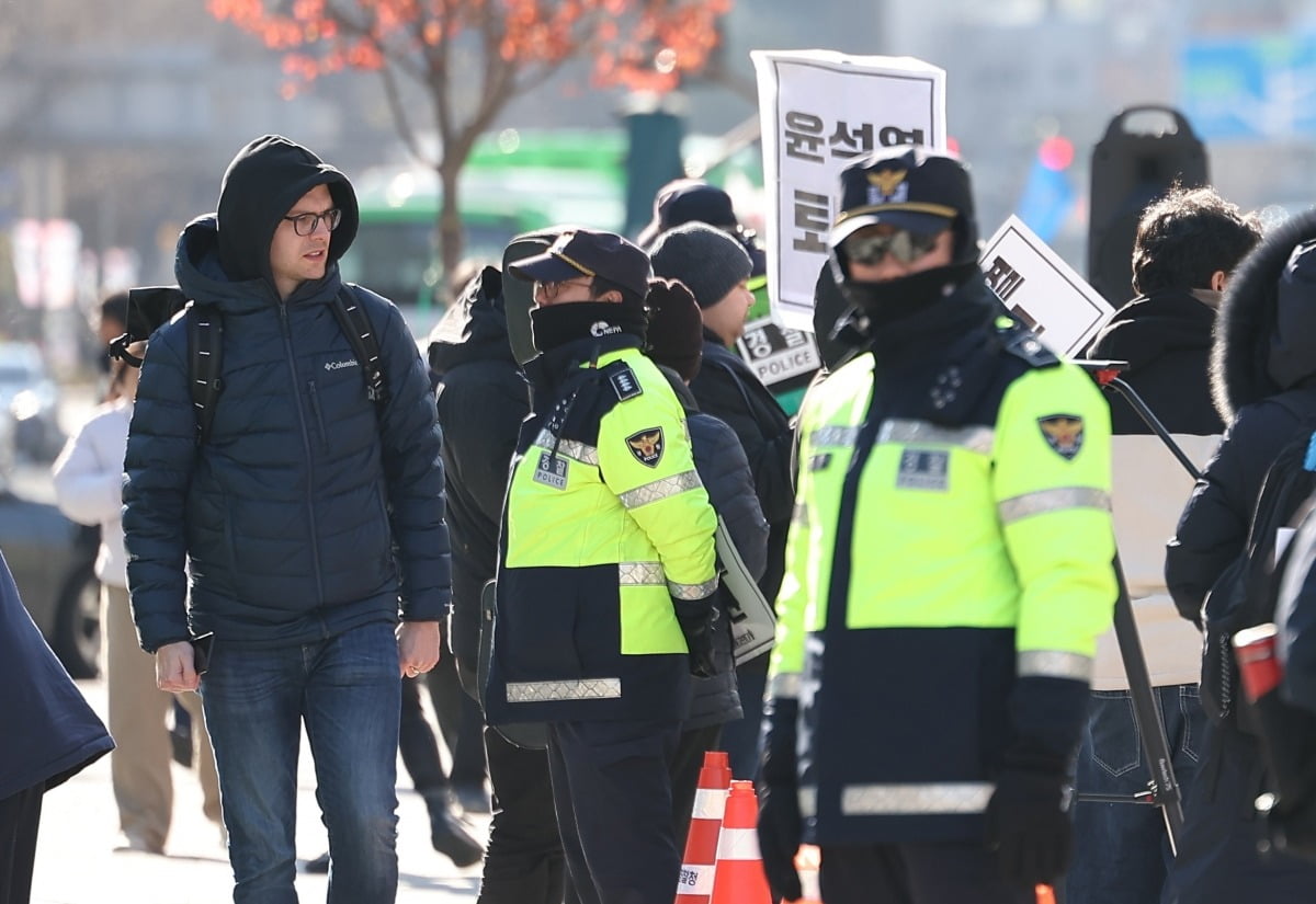 윤석열 대통령이 긴급 대국민 담화를 통해 비상계엄 해제를 선언한 4일 오전 서울 종로구 광화문광장에서 한 외국인 관광객이 계엄 반대 집회를 지켜보고 있다. 사진=연합뉴스