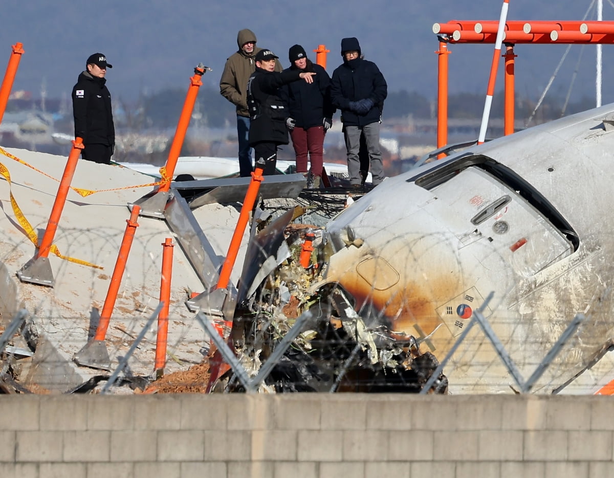  31일 오후 전남 무안군 무안국제공항 제주항공 여객기 참사 현장에서 미국 국가교통안전위원회(NTSB)와 보잉사 관계자, 국토부 항공철도사고조사위원회가 참사 원인으로 지목되고 있는 로컬라이저(방위각표시시설)가 있는 둔덕 위에 올라 사고 기체를 바라보고 있다. /사진=연합뉴스