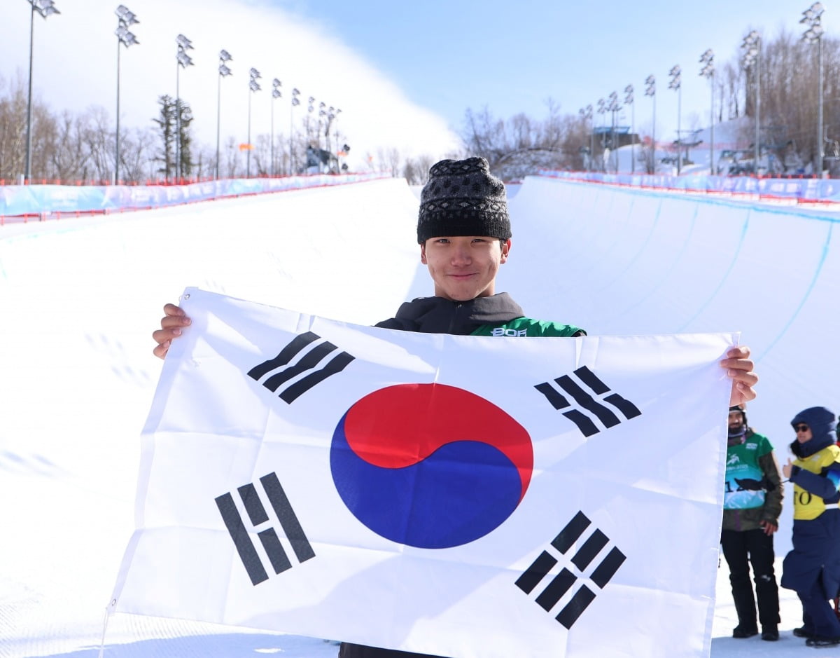 김건희가 13일 중국 야부리 스키리조트에서 열린 하얼빈 동계 아시안게임 스노보드 남자 하프파이프 결선에서 금메달을 차지한 뒤 태극기를 들고 포즈를 취하고 있다. 이날 경기는 강풍으로 취소돼 김건희는 예선 성적 78점으로 1위를 확정했다. 연합뉴스