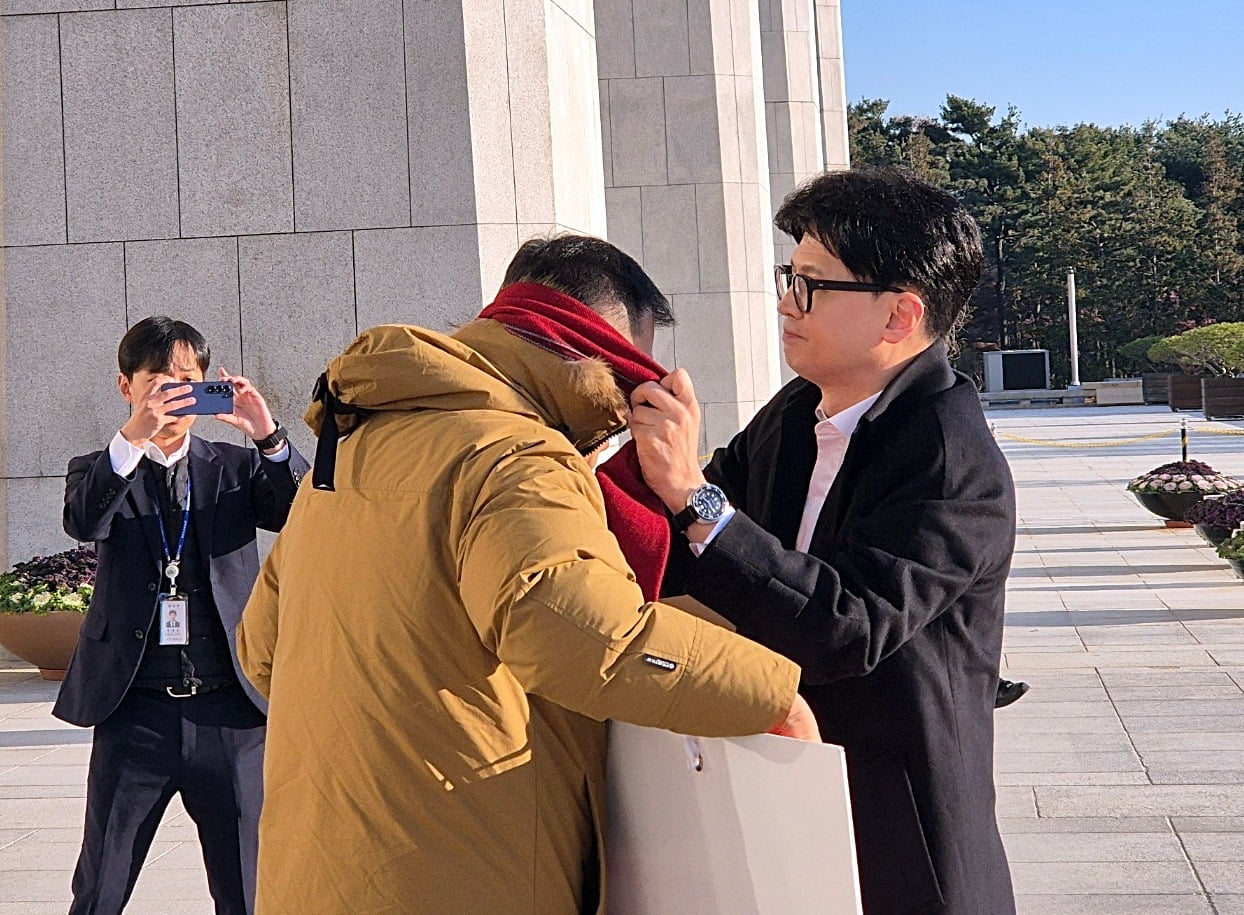 지난해 12월 14일 오전 국민의힘 업 카지노 대표가 국회 본청 앞에서 탄핵 찬성을 촉구하며 1인 시위를 하던 국민의힘 김상욱 의원에게 다가가 자기 목에 두르고 있던 빨간색 목도리를 풀어 김 의원에게 둘러주고 있다. / 사진=연합뉴스