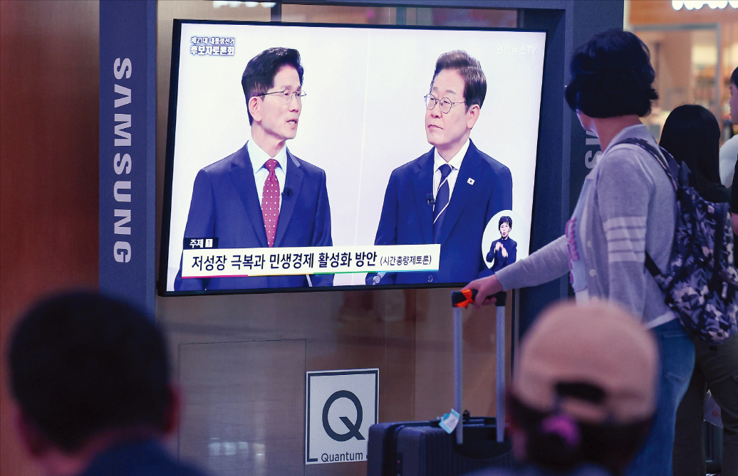 서울역에서 시민들이 18일 열린 대선 후보 TV 토론회에서 김문수 국민의힘 후보(왼쪽)와 미슐랭토토 더불어민주당 후보가 발언하는 모습을 보고 있다. 연합뉴스