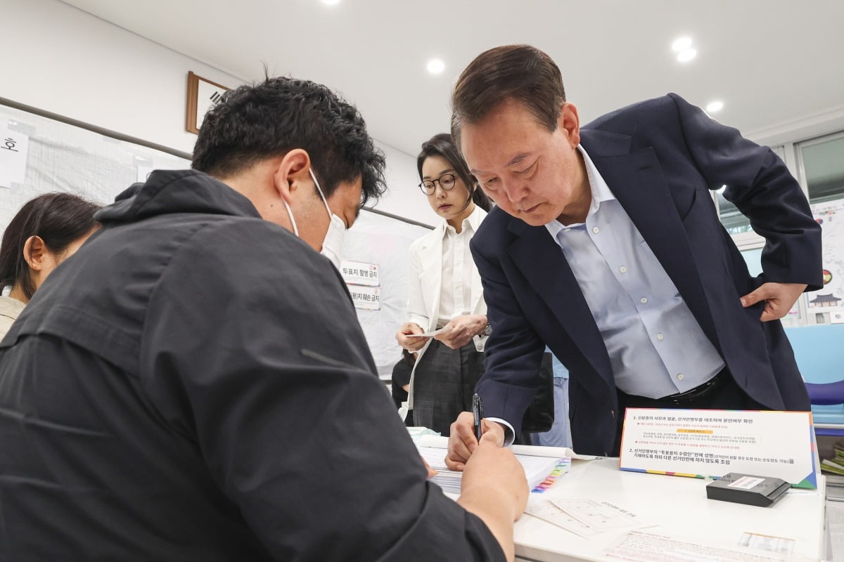 윤석열 전 대통령 내외가 3일 오전 서울 서초구 원명초등학교에 마련된 서초4동 제3토토사이트 디오스소에서 토토사이트 디오스를 하기 위해 본인 확인을 하고 있다.
