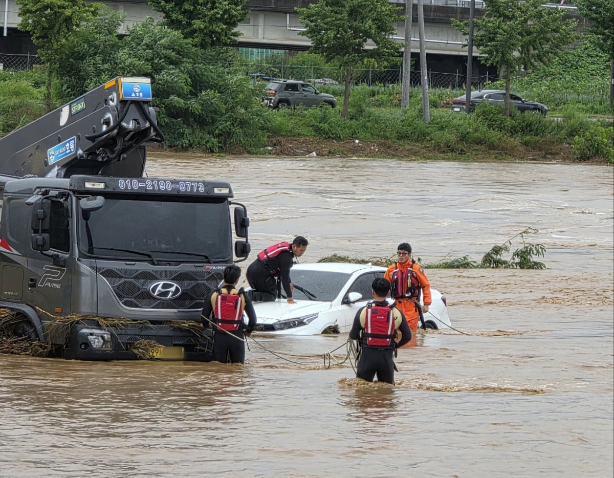밤사이 쏟아진 집중폭우로 침수 피해가 발생한 17일 충남 아산시 배방읍 곡교천변에서 소방대원들이 불어난 빗물에 쓰러진 시설물과 침수차량을 살펴보고 있다.  / 사진=뉴스1