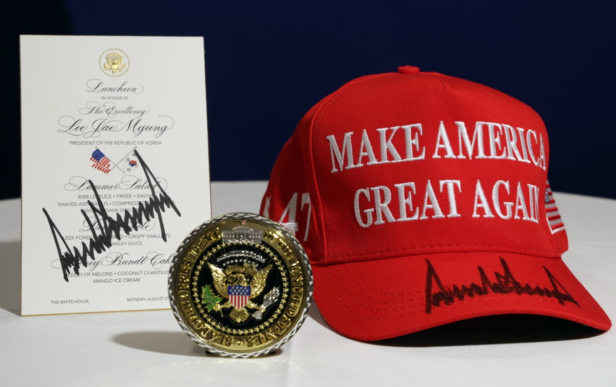 대통령실이 25일(현지시간) 공개한 도널드 트럼프 미국 대통령이 워싱턴DC 백악관에서 정상회담 후 이재명 대통령에게 준 선물. 백악관 기념 메달과 트럼프 대통령이 사인을 한 '마가'(MAGA·Make America Great Again·미국을 다시 위대하게) 모자와 오찬 메뉴판. /사진=연합뉴스