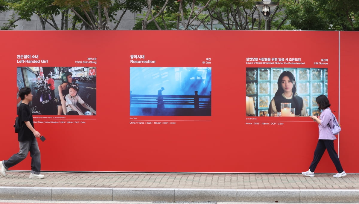 제30회 부산국제영화제(BIFF) 개막을 이틀 앞둔 15일 부산 해운대구 영화의전당 앞에 설치된 포스터 앞으로 시민이 지나가고 있다. /연합