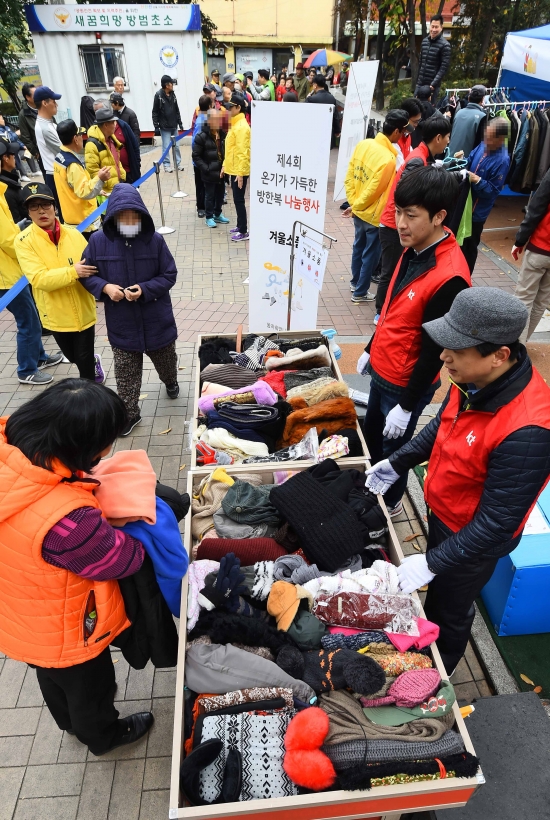 KT그룹 임직원 봉사단원들이 7일 서울 용산구 동자동 새꿈어린이공원에서 열린 '온기가 가득한 방한복 나눔' 행사에서 쪽방촌 주민들에게 방한복을 나눠주고 있다./김범준기자bjk07@hankyung.com